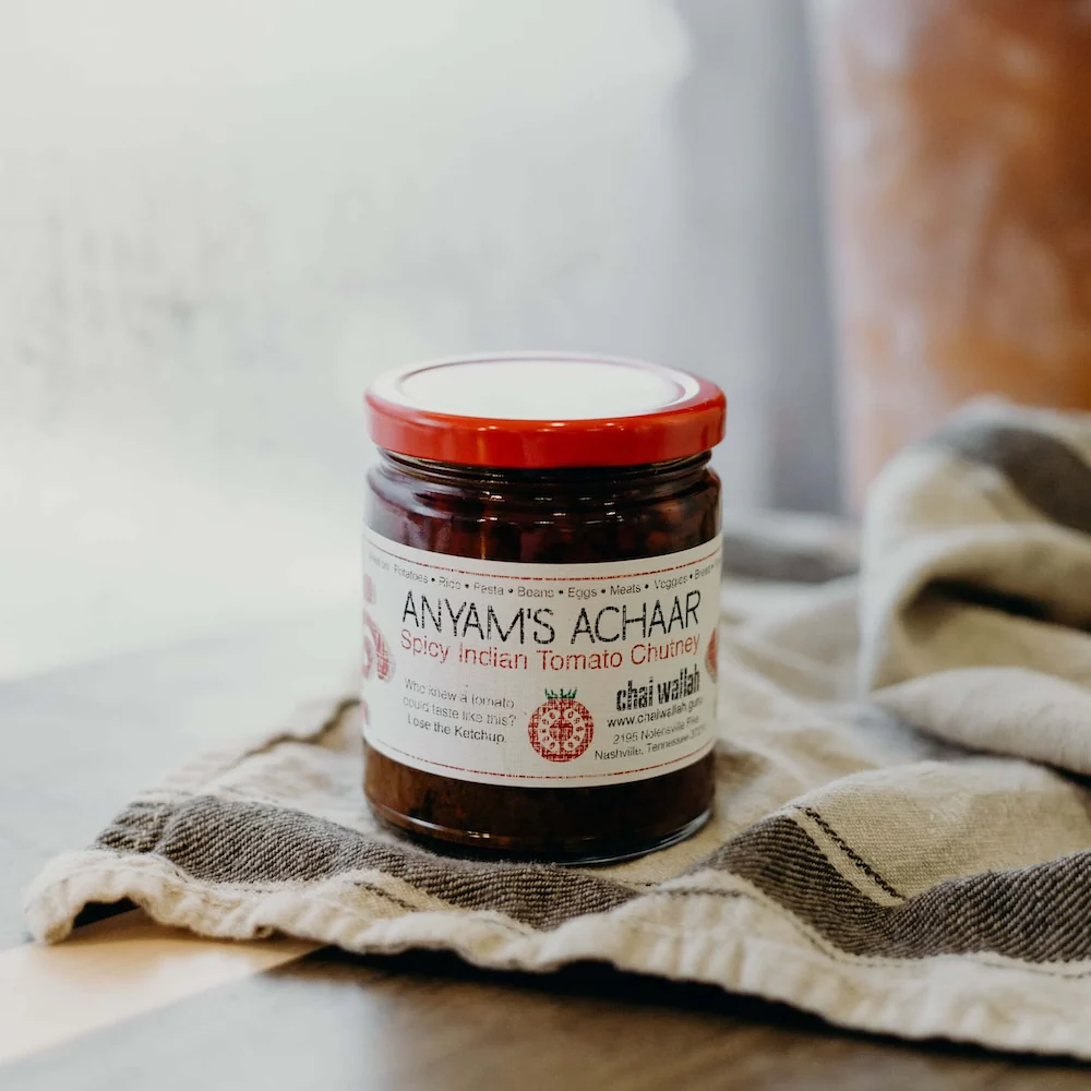 jar of anyam's achaar with a towel under it on a wooden table
