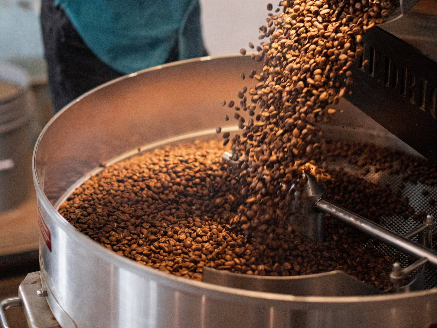 coffee beans being dumped from a roaster into a circular catcher