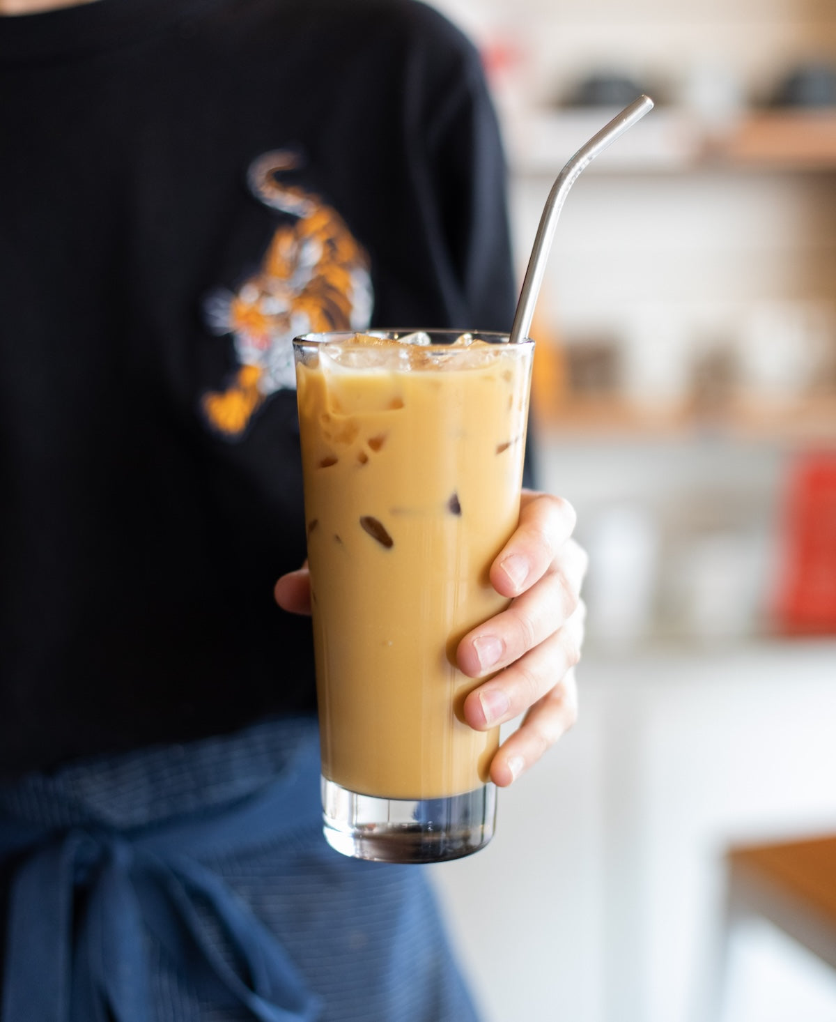 iced latte in a glass with metal straw being held by a barista