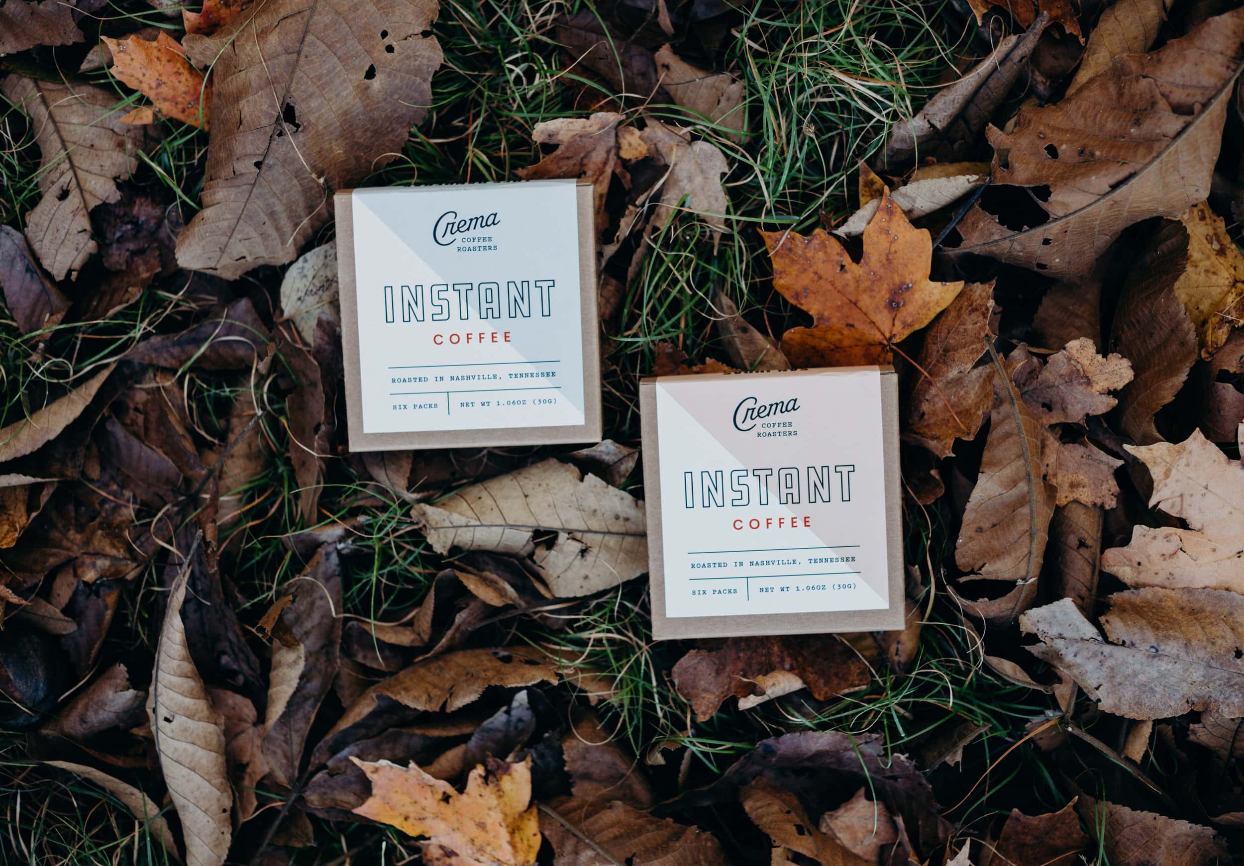 2 boxes of crema instant coffee lying on a bed a fall leaves